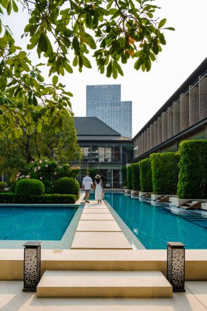 Foto de Hotel de lujo de 5 estrellas con piscina en Asia. Un par de hombres y mujeres de vacaciones en un hotel de lujo, hombres y mujeres junto a la piscina por la noche - Imagen libre de derechos