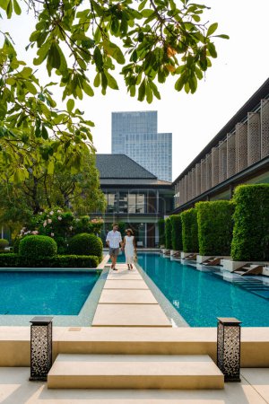 Téléchargez les photos : Luxe hôtel 5 étoiles piscine en Asie. Un couple d'hommes et de femmes en vacances dans un hôtel de luxe, hommes et femmes au bord de la piscine - en image libre de droit