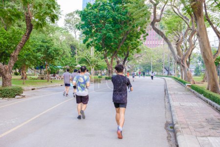 Téléchargez les photos : Lumpini parc Bangkok Thaïlande Mars 2023, les gens qui courent dans le parc avec un ciel pollué par l'air pm 2,5 smog - en image libre de droit
