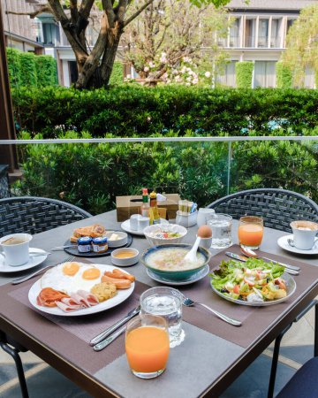 Foto de Mesa de desayuno en un hotel de lujo con huevos pan y sopa de arroz con jugo de naranja y café. - Imagen libre de derechos