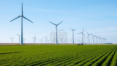 Foto de Grandes turbinas de molinos de viento en los Países Bajos, transición energética en los Países Bajos con campos agrícolas verdes y parque de molinos de viento. - Imagen libre de derechos