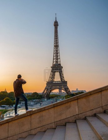 Foto de Jóvenes fotografiando la Torre Eiffel al amanecer, un hombre tomó una foto de la Torre Eiffel de París. - Imagen libre de derechos