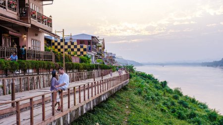Photo for A couple of men and women visit Chiang Khan village North Eastern Thailand alongside the Mekong river. A traditional village with wooden house - Royalty Free Image