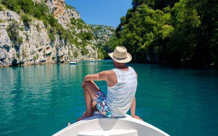 Photo for Young men in front of a boat at Gorges Du Verdon lake of Sainte Croix, Provence, France, Provence Alpes Cote d Azur, turquoise lake with boats in France Provence - Royalty Free Image