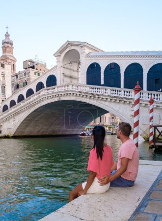 Foto de Un par de hombres y mujeres en un viaje por la ciudad en Venecia Italia sentado en el paseo marítimo del puente de Rialto en Venecia, Italia. - Imagen libre de derechos