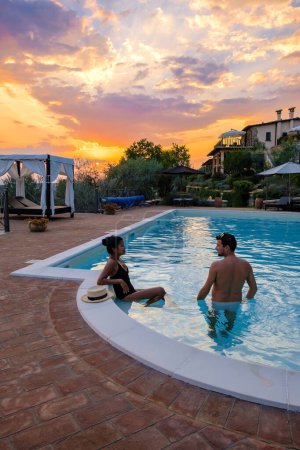 Photo for Luxury country house with swimming pool in Italy. Pool and old farmhouse during sunset in central Italy. Couple on Vacation at a luxury villa in Italy, men and woman watching sunset during vacation - Royalty Free Image