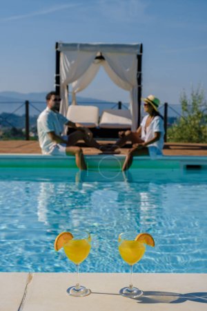 Téléchargez les photos : Villa de luxe avec piscine en Italie. Couple en vacances dans une villa de luxe en Italie, hommes et femmes regardant le coucher du soleil. et boire des cocktails - en image libre de droit