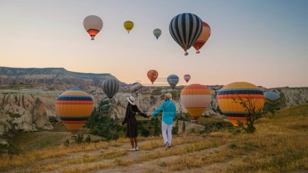 Téléchargez les photos : Kapadokya Cappadoce Turquie, un jeune couple heureux pendant le lever du soleil regardant les montgolfières de Kapadokya Cappadoce Turquie pendant les vacances - en image libre de droit