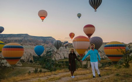 Téléchargez les photos : Femmes asiatiques et hommes caucasiens d'âge moyen lors d'un voyage en Kapadokya Cappadoce Turquie, un jeune couple heureux pendant le lever du soleil regardant les montgolfières de Kapadokya Cappadoce Turquie pendant les vacances - en image libre de droit
