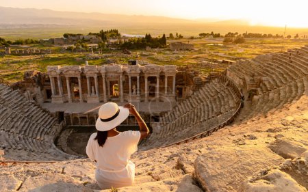Photo for Hierapolis ancient city Pamukkale Turkey, sunset by the ruins Unesco site, Hierapolis ancient city Pamukkale Turkey Young Asian women with hat watching the sunset at Hierapolis Pamukkale - Royalty Free Image