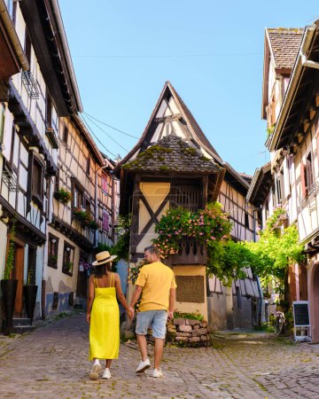 Téléchargez les photos : Un couple d'hommes et de femmes en vacances à Eguisheim France Belle vue sur la ville romantique colorée d'Eguisheim près de Colmar pendant l'été - en image libre de droit