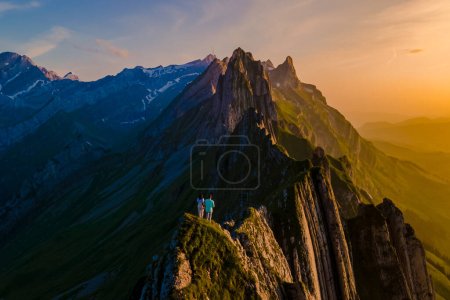 Foto de Schaeffler mountain ridge swiss Alpstein, Appenzell Suiza, una cresta del pico Schaeffler por Berggasthaus Schafler, Suiza. pareja de hombres y mujeres en las montañas durante la puesta del sol - Imagen libre de derechos