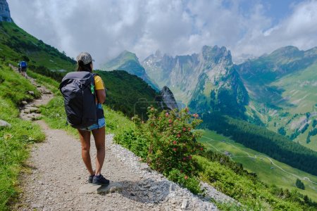 Téléchargez les photos : Randonnées pédestres dans les Alpes suisses pendant les vacances d'été avec un sac à dos et des bottes de randonnée. femme marchant sur le sentier Saxer Lucke - en image libre de droit