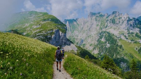 Foto de Mujeres asiáticas haciendo senderismo en las montañas de los Alpes suizos durante las vacaciones de verano con una mochila y botas de senderismo. mujer caminando por el sendero Sajer Lucke una popular ruta de senderismo en Suiza - Imagen libre de derechos