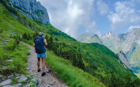 Téléchargez les photos : Femmes asiatiques marchant dans les Alpes suisses pendant les vacances d'été avec un sac à dos et des bottes de randonnée. femme marchant sur le sentier Saxer Lucke un sentier de randonnée populaire en Suisse - en image libre de droit