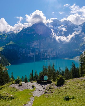 Téléchargez les photos : Quelques hommes et femmes visitant le lac Oeschinensee. Une magnifique scène en plein air dans les Alpes suisses avec la montagne Bluemlisalp, Kandersteg village emplacement, Suisse, Europe. - en image libre de droit