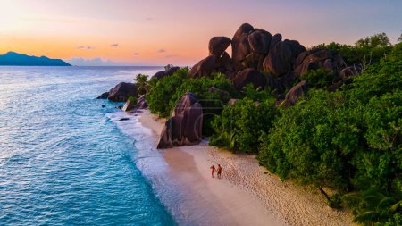 Téléchargez les photos : Anse Source dArgent beach, La Digue Island, Seyshelles, Drone vue aérienne de La Digue Seychelles couple hommes et femmes marchant sur la plage pendant le coucher du soleil lors de vacances de luxe - en image libre de droit