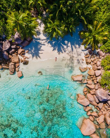 Téléchargez les photos : Praslin Seychelles île tropicale avec withe plages et palmiers, couple d'hommes et de femmes d'âge moyen en vacances aux Seychelles visitant la plage tropicale Anse Lazio Praslin Seychelles. vue sur drone - en image libre de droit