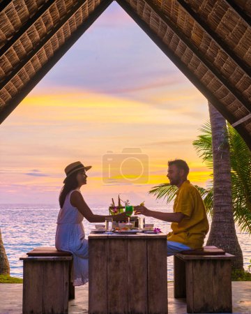 Romantic dinner on the beach with Thai food during sunset on the Island of Koh Mak Thailand. Couple of men and women having a romantic dinner on the beach