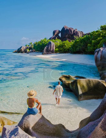 Téléchargez les photos : Anse Source dArgent plage, Île La Digue, Seychelles, couple hommes et femmes marchant sur la plage au coucher du soleil lors de vacances de luxe aux Seychelles - en image libre de droit