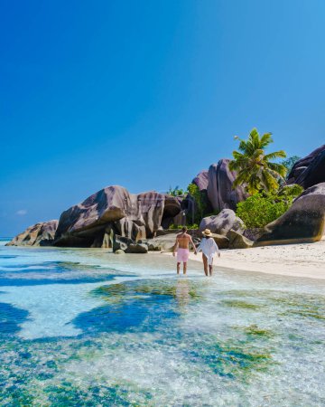 Foto de Anse Source dArgent beach, La Digue Island, Seychelles, view.of tropical Island, couple men and woman walking at the beach during sunset at a luxury vacation - Imagen libre de derechos