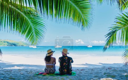Téléchargez les photos : Praslin Seychelles tropical island with withe beaches and palm trees, couple of men and women mid age on vacation at Seychelles visiting the tropical beach Anse Lazio Praslin Seychelles. drone view - en image libre de droit