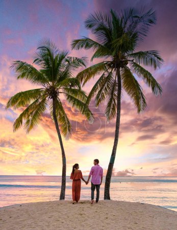 Photo for Couple on the beach with palm trees watching the sunset at the tropical beach of Saint Lucia or St Lucia Caribbean. men and women on vacation in St Lucia a tropical island with palm trees - Royalty Free Image