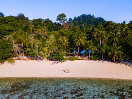 Photo for Drone view at the beach of Koh Kradan island in Thailand with a couple of men and woman walking on the beach. - Royalty Free Image