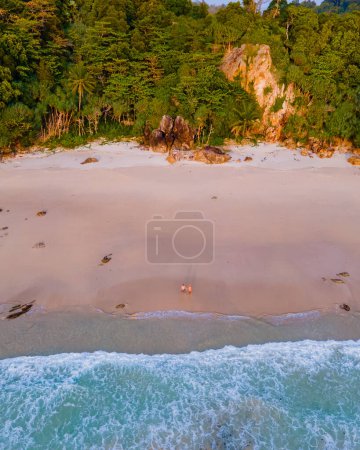 Photo for Drone view at the beach of Koh Kradan island in Thailand , with a couple of men and woman walking on the beach of sunset beach - Royalty Free Image