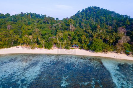 Photo for Drone view at the beach of Koh Kradan island in Thailand, with a couple of men and women walking on the beach with palm trees - Royalty Free Image