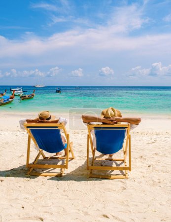 Téléchargez les photos : Chaises longues sur la plage de l'île de Koh Kradan en Thaïlande, avec un couple d'hommes et de femmes se détendre sur la plage - en image libre de droit