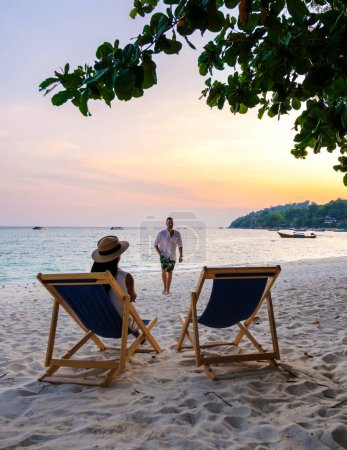 Photo for Beach chairs at the beach of Koh Kradan island in Thailand, with a couple of men and women relaxing on the beach - Royalty Free Image