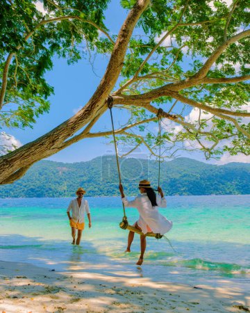 Téléchargez les photos : Koh Ra Wi île en Thaïlande près de Ko Lipe, avec un couple d'hommes et de femmes se détendre sur la plage du parc national de Tarutao - en image libre de droit