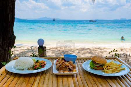Téléchargez les photos : Déjeuner à la plage de l'île de Koh Kradan en Thaïlande, déjeuner avec de la nourriture thaï et hamburger avec des frites - en image libre de droit