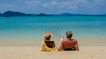 Téléchargez les photos : L'arrière d'un couple d'hommes et de femmes assis sur la plage de l'île de Koh Kradan en Thaïlande pendant les vacances - en image libre de droit