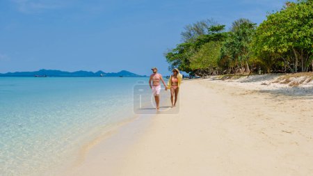 Téléchargez les photos : Un couple d'hommes et de femmes sur la plage de l'île de Koh Kradan Thaïlande, hommes et femmes se détendre sur la plage avec une turque couleur océan par une journée ensoleillée - en image libre de droit