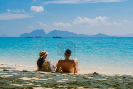 Foto de La parte trasera de un par de hombres y mujeres sentados en la playa de la isla de Koh Kradan en Tailandia durante las vacaciones en un día soleado - Imagen libre de derechos