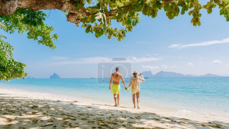 Foto de La parte trasera de un par de hombres y mujeres sentados en la playa de la isla de Koh Kradan en Tailandia durante unas vacaciones en un día soleado - Imagen libre de derechos