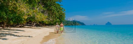 Foto de La parte trasera de un par de hombres y mujeres sentados en la playa de la isla de Koh Kradan en Tailandia durante las vacaciones en un día soleado en vacaciones en la playa - Imagen libre de derechos