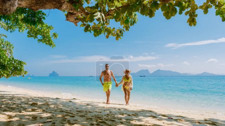 Téléchargez les photos : Un couple d'hommes et de femmes marchant sur la plage de l'île de Koh Kradan en Thaïlande pendant des vacances par une journée ensoleillée en Thaïlande - en image libre de droit