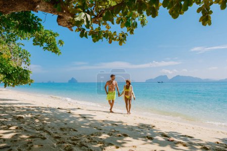 Téléchargez les photos : L'arrière d'un couple d'hommes et de femmes assis sur la plage de l'île de Koh Kradan en Thaïlande pendant les vacances par une journée ensoleillée sur la plage - en image libre de droit