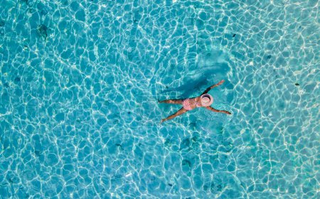Téléchargez les photos : Vue par drone d'une femme nageant dans l'océan bleu turqouse de l'île de Koh Kradan en Thaïlande - en image libre de droit