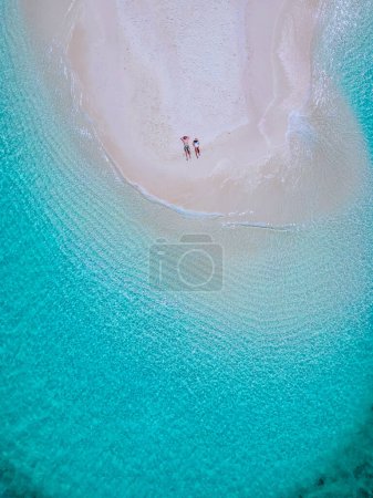 Foto de Pareja de hombres y mujeres en un banco de arena blanca en el océano de Koh Lipe Island sur de Tailandia, con turqouse océano de color y arena blanca playa arenosa en Ko Lipe en un día soleado - Imagen libre de derechos