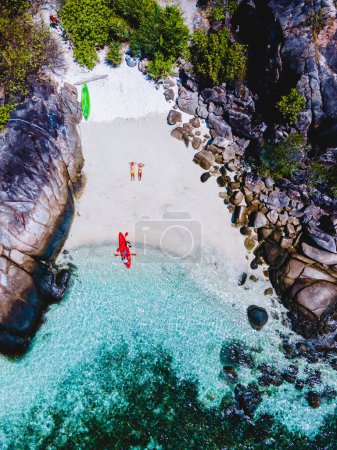 Téléchargez les photos : Couple sur la plage de l'île de Kla en face de l'île de Koh Lipe sud de la Thaïlande avec turqouse couleur océan et plage de sable blanc avec un kayak à Ko Lipe par une journée ensoleillée - en image libre de droit