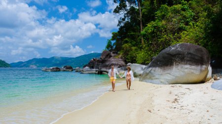 Photo for Couple of men and women on the beach in swimwear at Koh Adang Island near Koh Lipe Island Southern Thailand with turqouse colored ocean and white sandy beach Tarutao National Park - Royalty Free Image