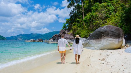 Téléchargez les photos : Couple d'hommes et de femmes sur la plage en maillots de bain à l'île de Koh Adang près de l'île de Koh Lipe en Thaïlande du Sud avec turqouse couleur océan et plage de sable blanc Tarutao National Park - en image libre de droit