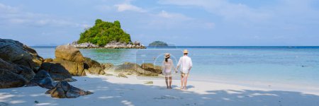 Téléchargez les photos : Koh Lipe Island Sud de la Thaïlande avec turqouse couleur océan et plage de sable blanc à Ko Lipe. un couple d'hommes et de femmes en vacances en Thaïlande marchant sur la plage - en image libre de droit