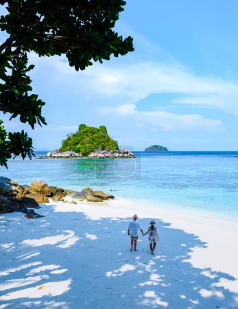 Téléchargez les photos : Koh Lipe Island Sud de la Thaïlande avec turqouse couleur océan et plage de sable blanc à Ko Lipe. un couple d'hommes et de femmes en vacances en Thaïlande marchant sur la plage - en image libre de droit