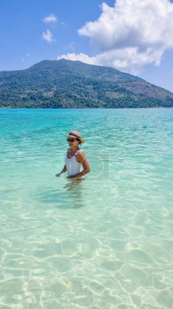Téléchargez les photos : Koh Lipe Island Sud de la Thaïlande avec turqouse couleur océan et plage de sable blanc à Ko Lipe. une femme asiatique en vacances en Thaïlande marchant sur la plage - en image libre de droit