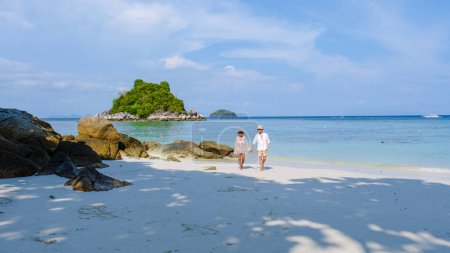 Téléchargez les photos : Un couple d'hommes et de femmes en vacances en Thaïlande marchant sur la plage, Koh Lipe Island sud de la Thaïlande avec turqouse couleur océan et plage de sable blanc à Ko Lipe - en image libre de droit